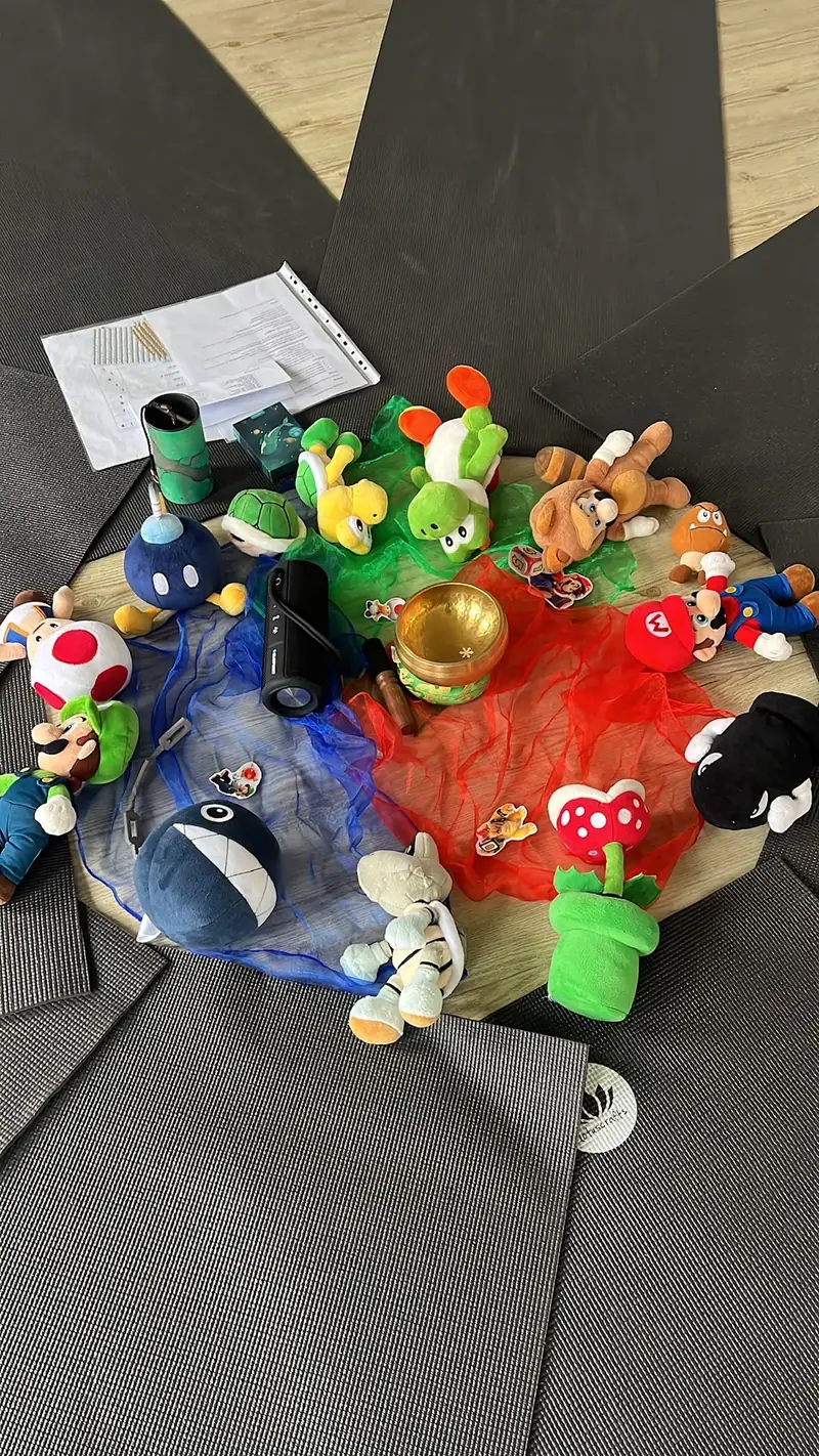 Plüschfiguren aus dem Pilz-Königreich liegen zwischen bunten Tüchern auf den Matten